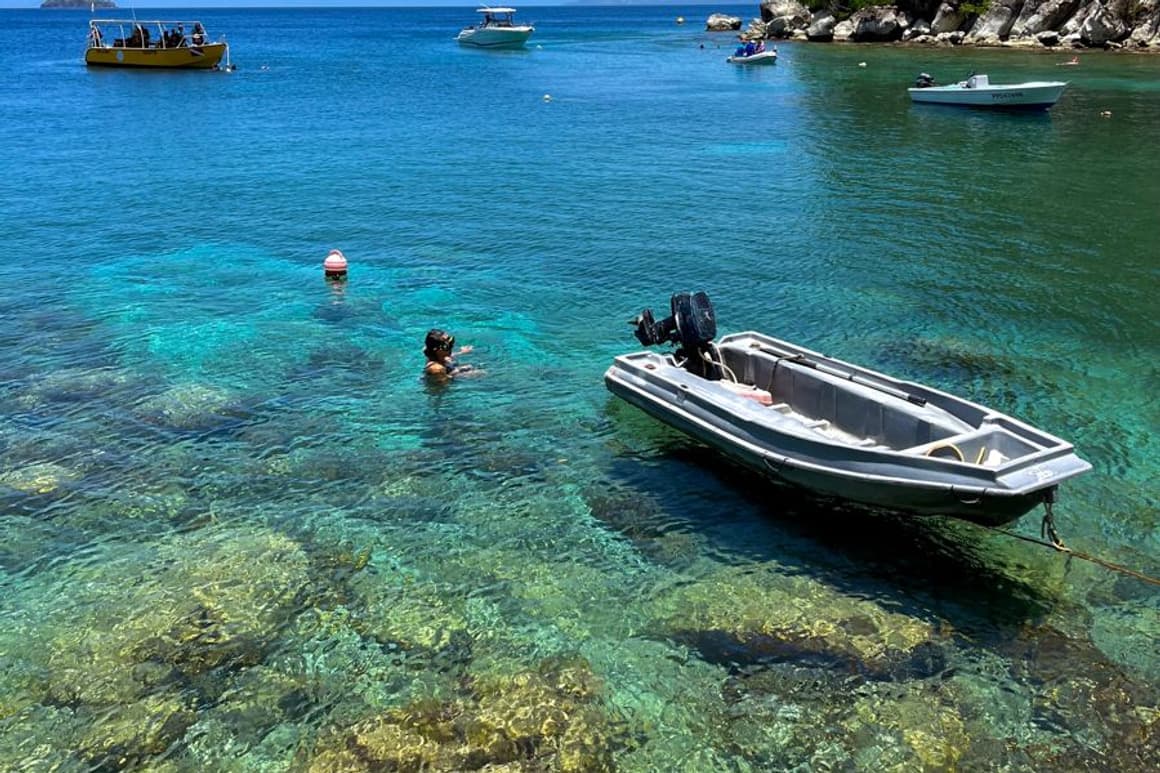 Crique aux fonds clairs, bateaux au mouillage au pied d’un morne boisé