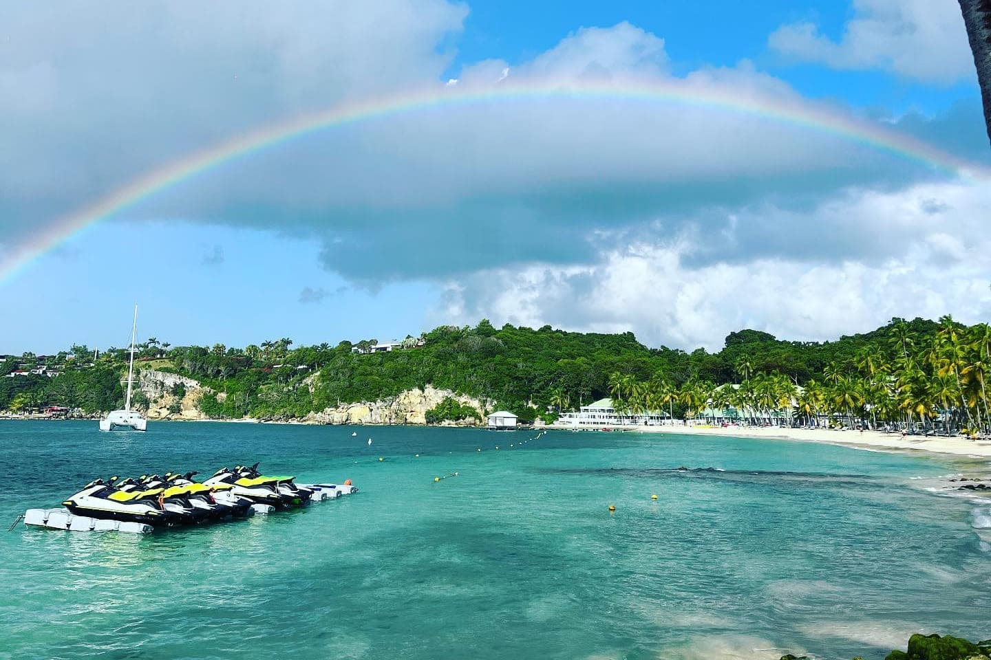 Un arc-en-ciel au-dessus de la baie, les jet skis amarrés devant la plage