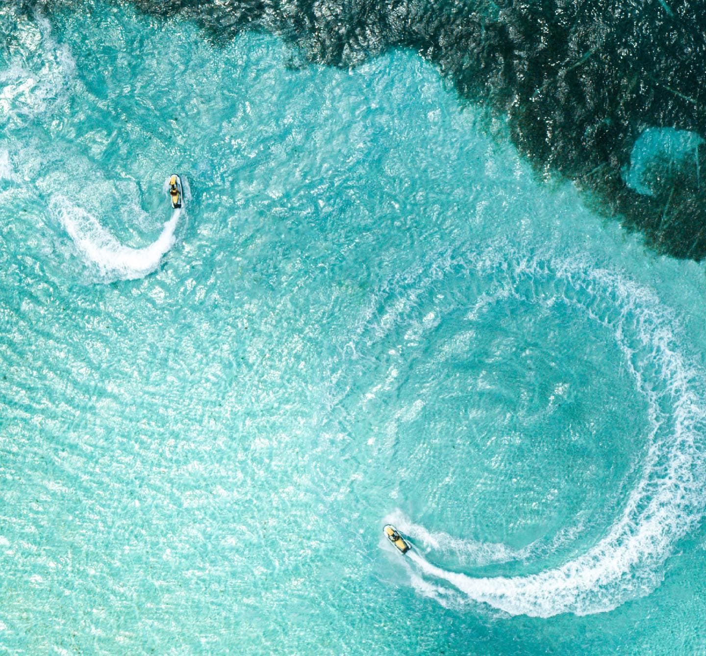 Deux jet skis traçant des cercles sur le lagon, vus du ciel
