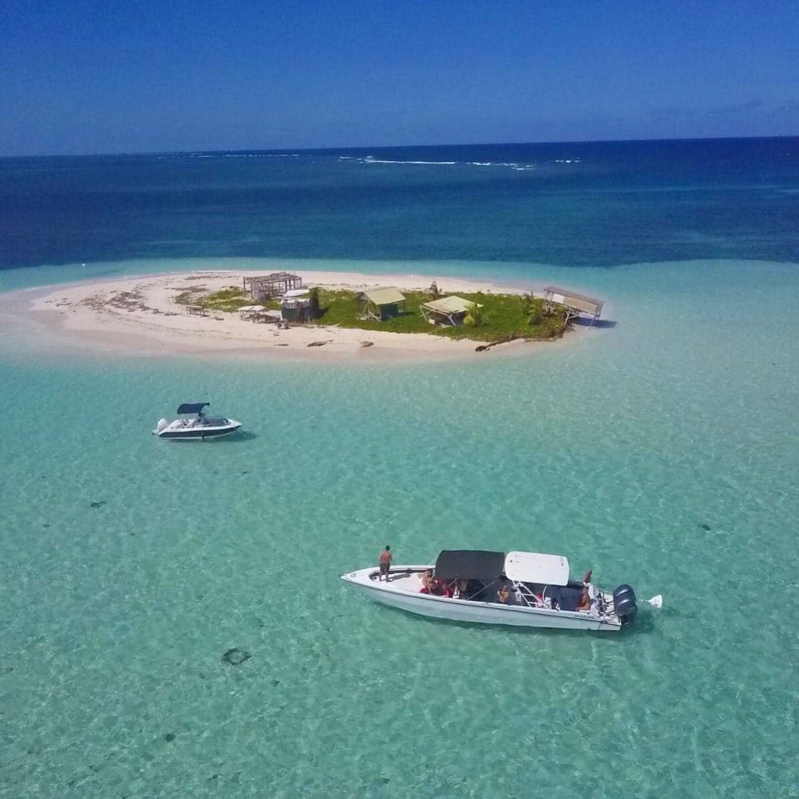 Îlet de sable blanc entouré d’eaux turquoise avec des bateaux au mouillage
