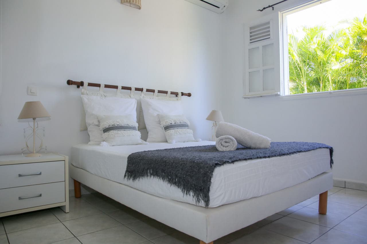 Deuxième chambre climatisée de la Villa Alizé, lit double ouvert sur la terrasse en bois
