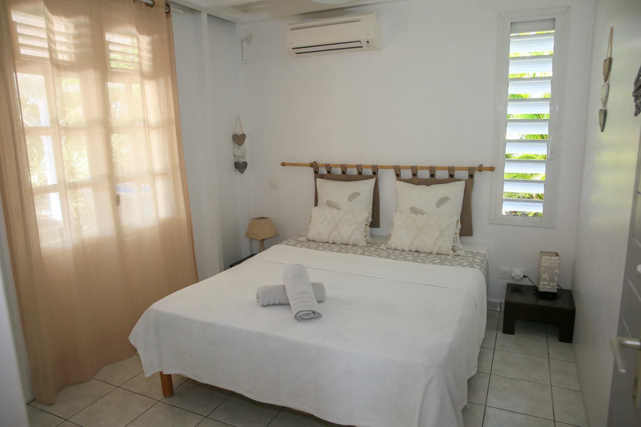 La deuxième chambre de la Villa Alizé, sa climatisation et sa fenêtre voilée