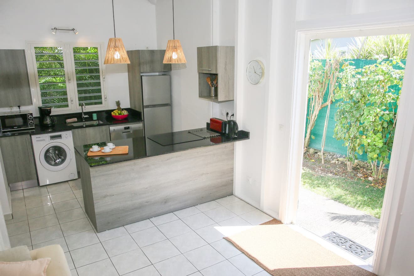 La cuisine de la Villa Alizé et sa porte ouverte sur le jardin