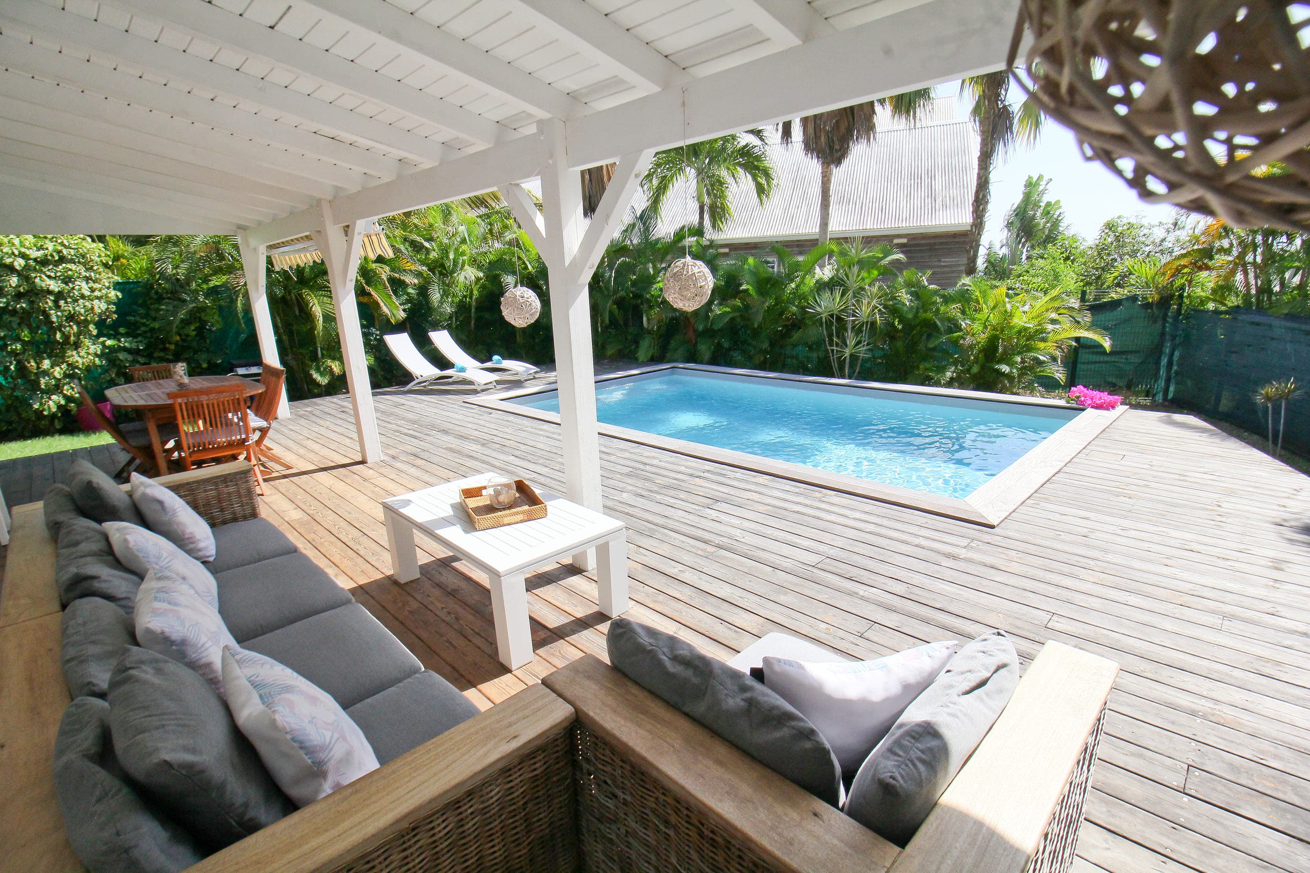 Salon d’extérieur en rotin sous la terrasse couverte de la Villa Alizé