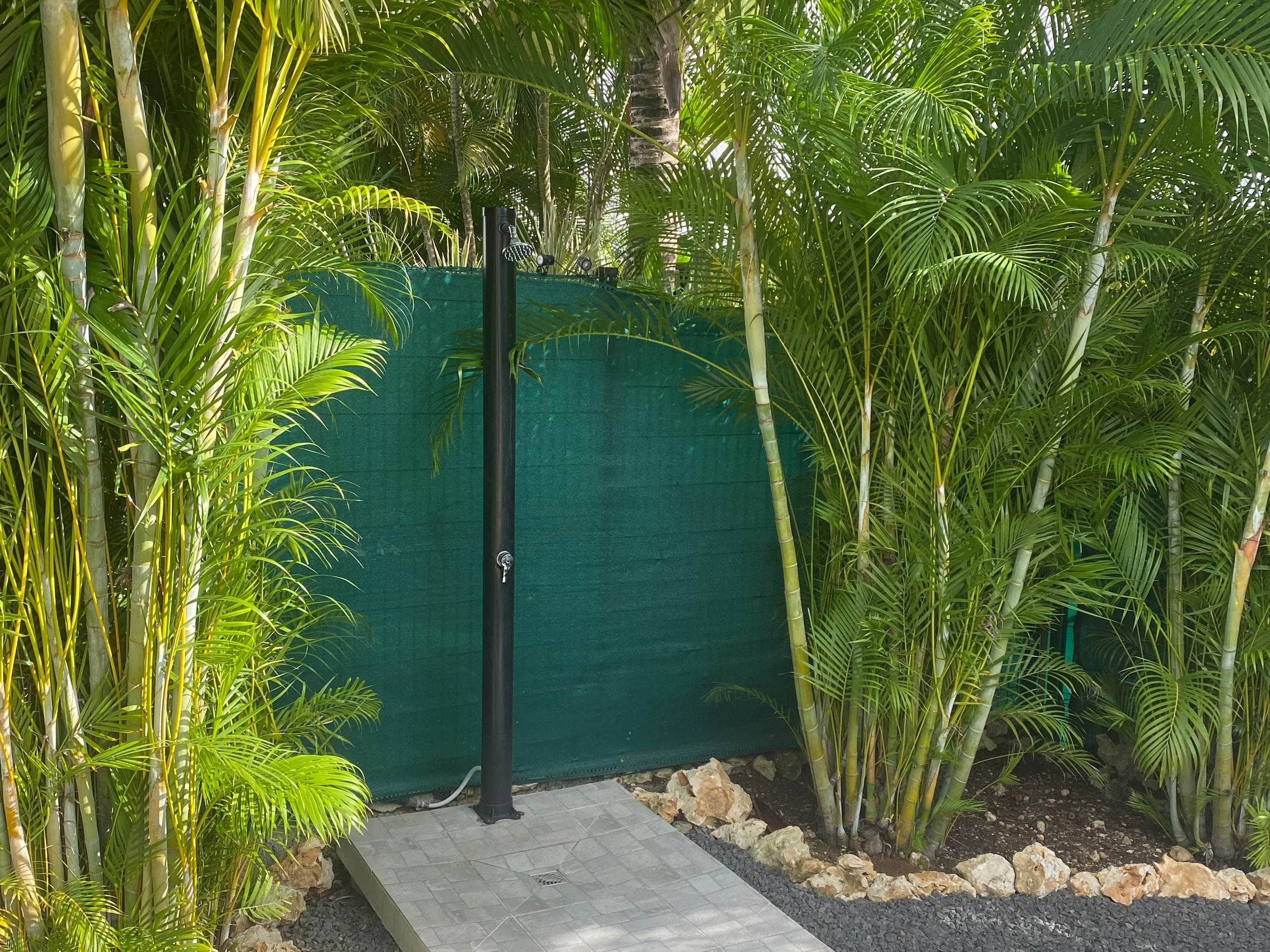 La douche extérieure de la Villa Alizé, adossée à son brise-vue au milieu des palmiers