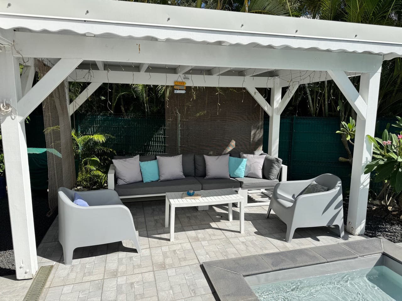 Le salon d’extérieur de la Villa Bahia sous la pergola, au bord de la piscine