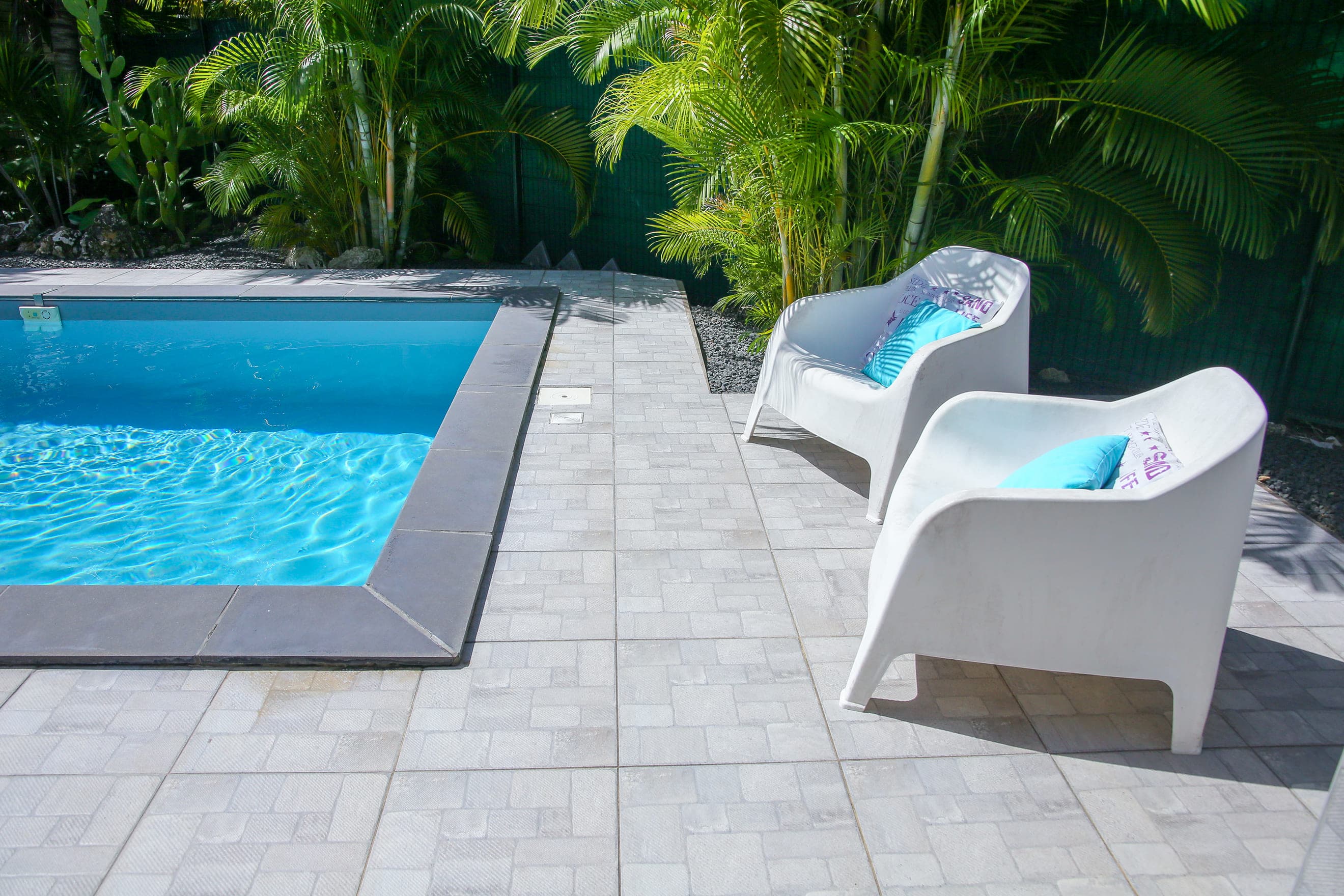 Deux bains de soleil blancs au bord de la piscine de la Villa Bahia